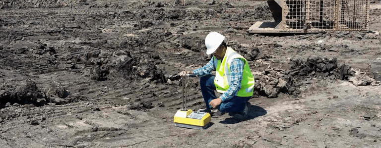 Geotechnical engineer conducting fieldwork at a construction site, examining soil samples and surveying the terrain.